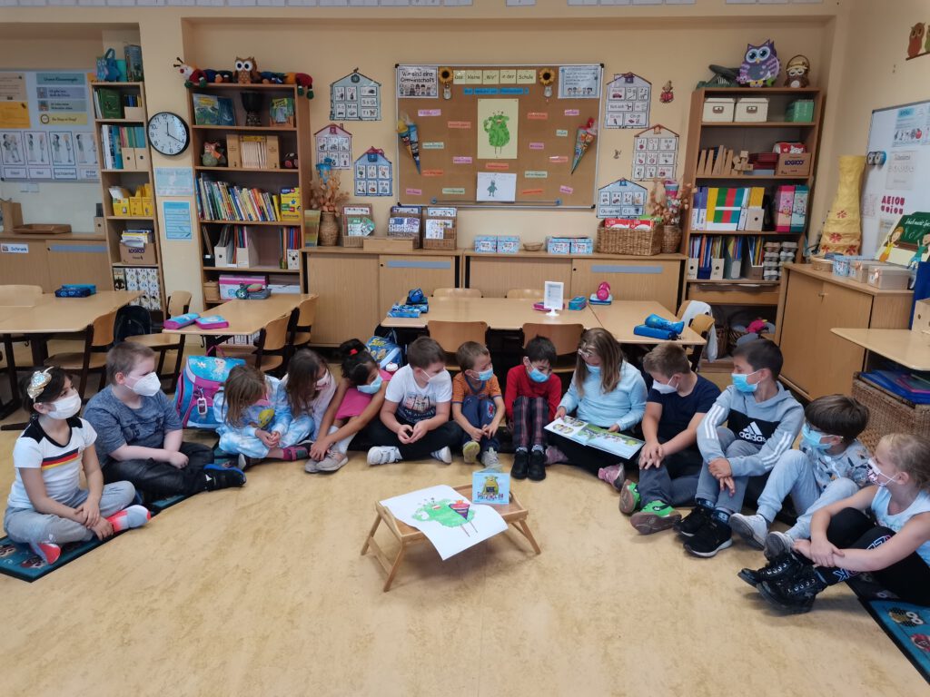 Lesezeit - Kinder sitzen im Kreis auf dem Boden