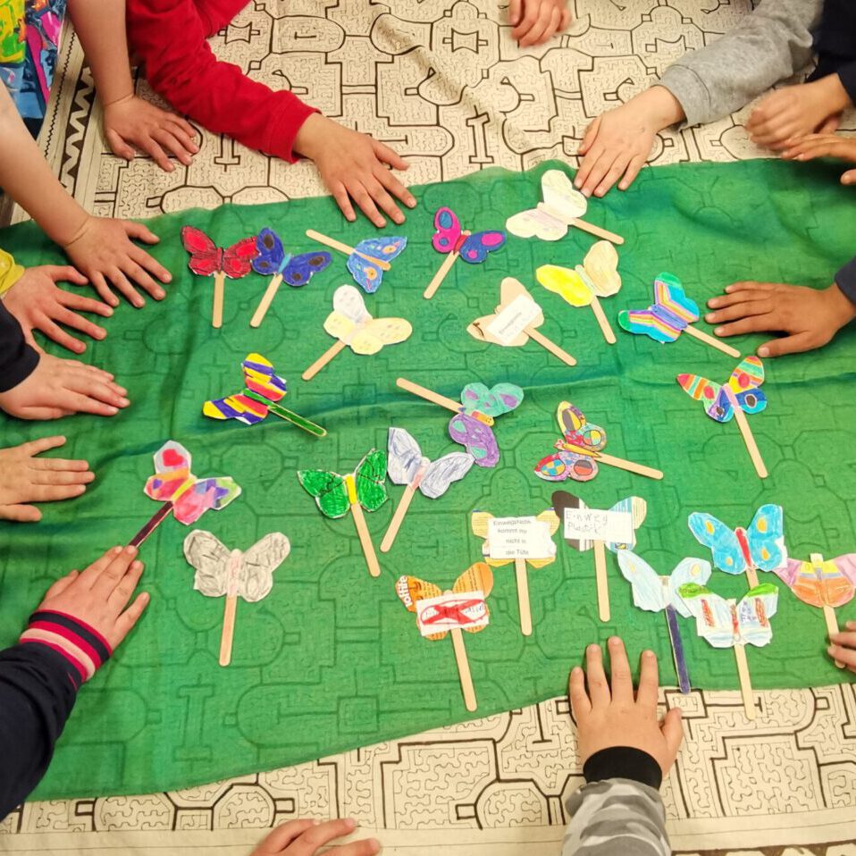 Viele Schmetterlinge aus Papier mit Kinderhänden