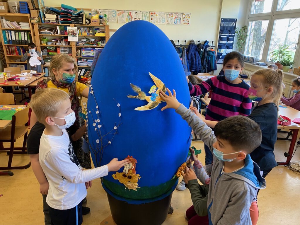 Kinder stecken Schmetterlinge an ein übergroßes Ei