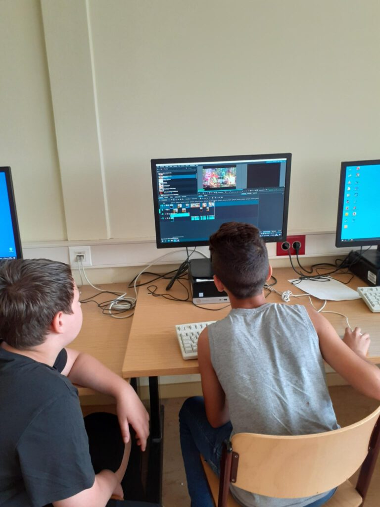zwei Jungs sitzen vor einem PC und bearbeiten Videos.