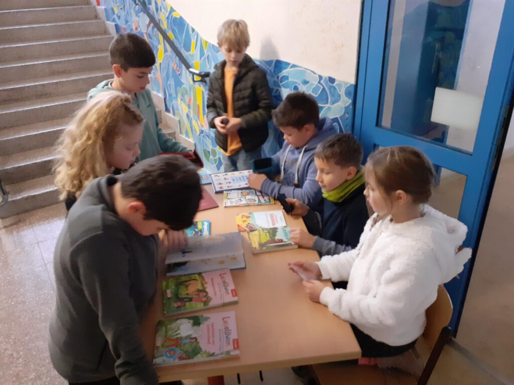 Viele Kinder stehen um einen Tisch voller Bücher. 