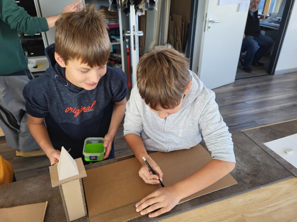 Zwei Jungs schneiden Pappe zu