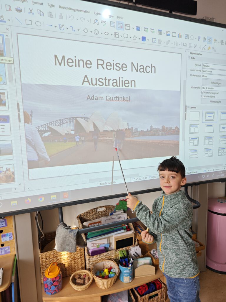 Ein Junge steht vor einem Whiteboard und zeigt auf ein Australienbild