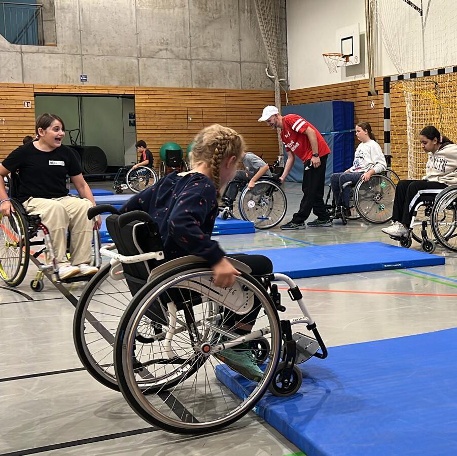 kinder der 5. Klasse im Rollstuhl in einer Turnhalle