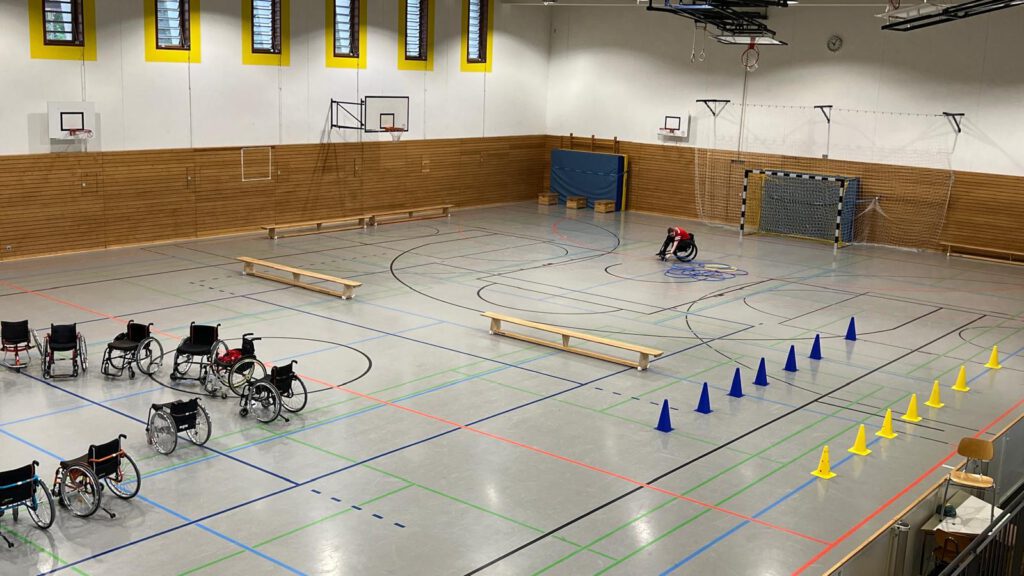 kinder der 5. Klasse im Rollstuhl in einer Turnhalle