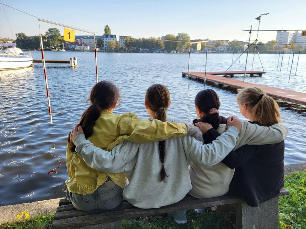 4 Mädchen auf einer Bank von hinten