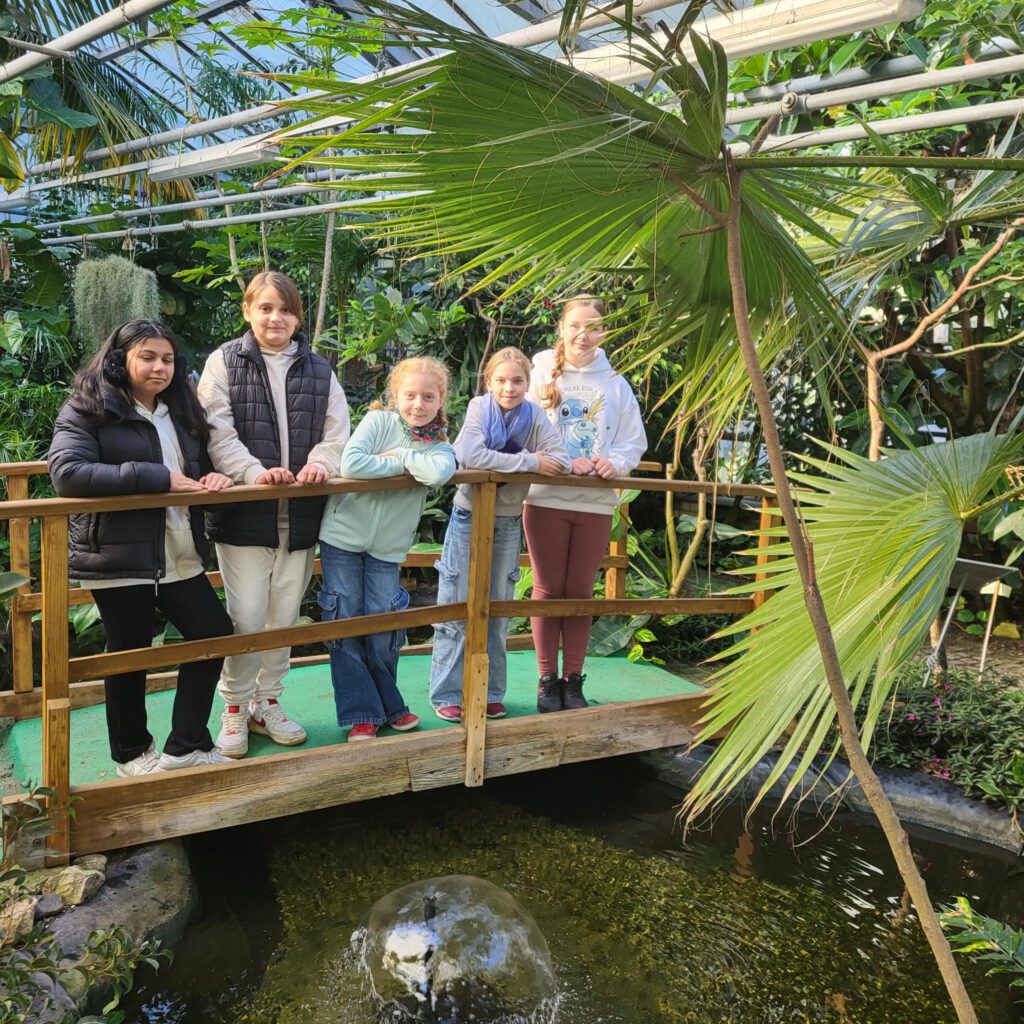 5 Mädchen stehen im Gewächshaus auf einer Brücke