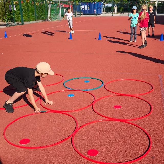 Ein Kind macht Sportübungen mit Reifen am Boden