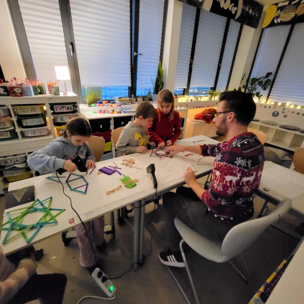 Kinder basteln mit Erzieher im Klassenraum