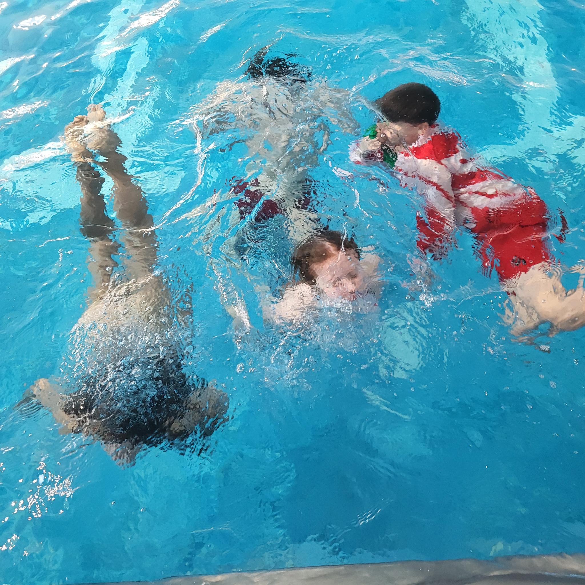 Kinder tauchen unter in einer Schwimmhalle