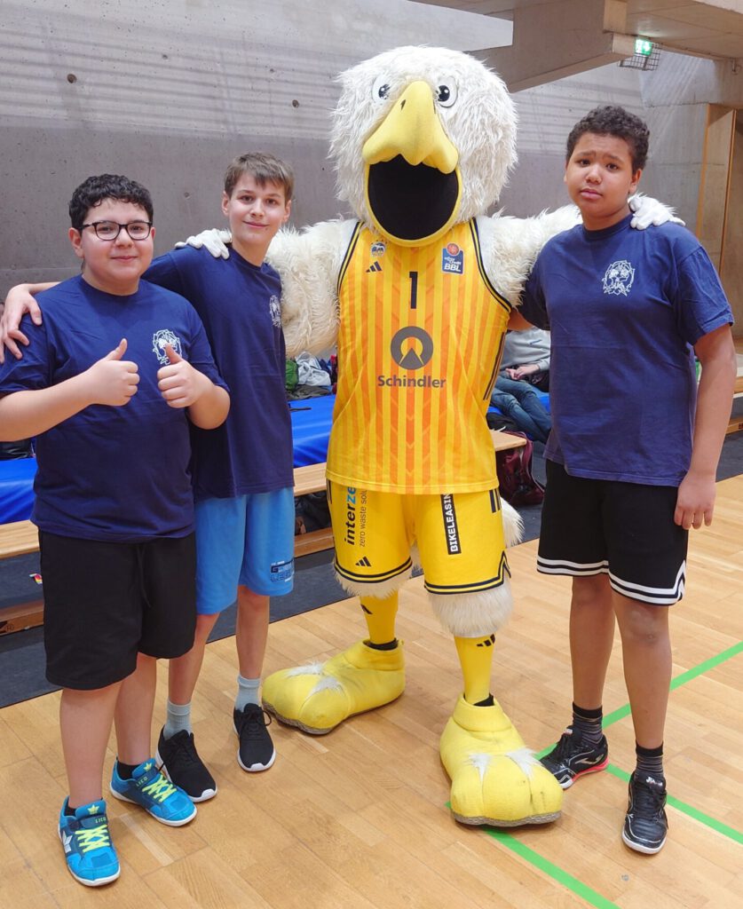 drei Kinder stehen auf dem Basketballfeld