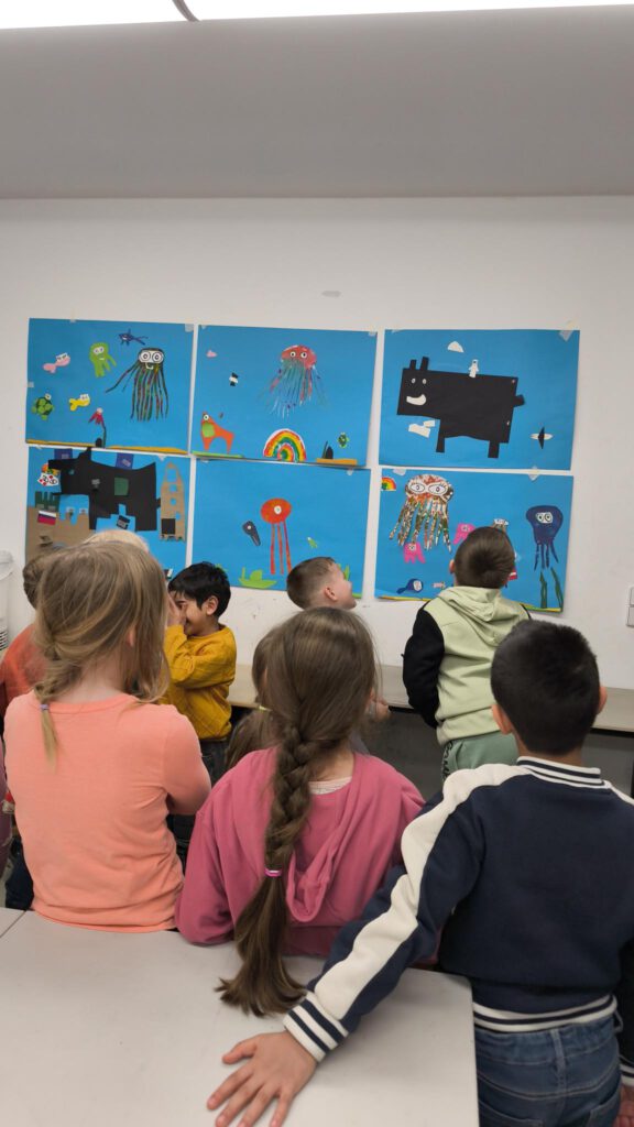 Kinder stehen vor ihren selbst gezeichneten Bildern